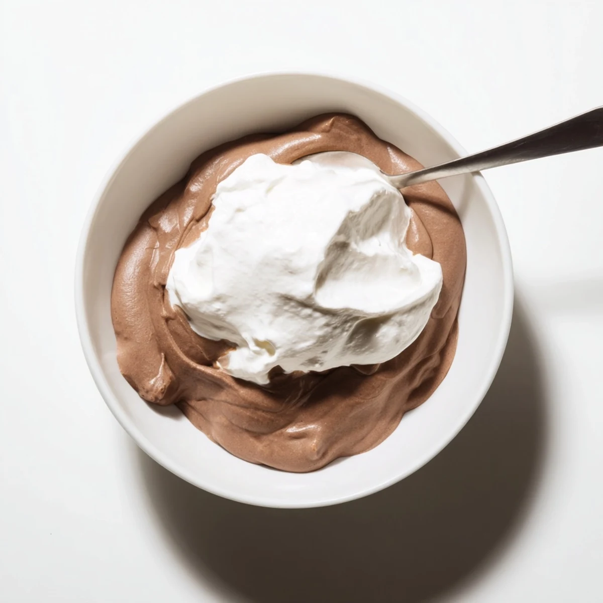 Silky chocolate pudding with whipped cream in a glass dish, rich and creamy for a comforting dessert.  