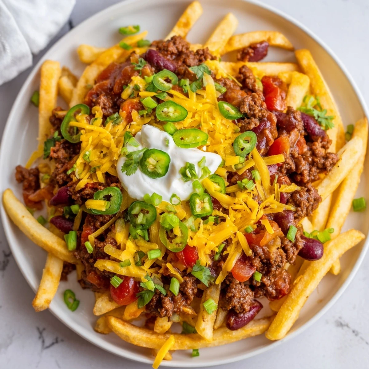 Hearty American chili cheese fries with ground beef, onions, and fresh cilantro garnish for sharing.