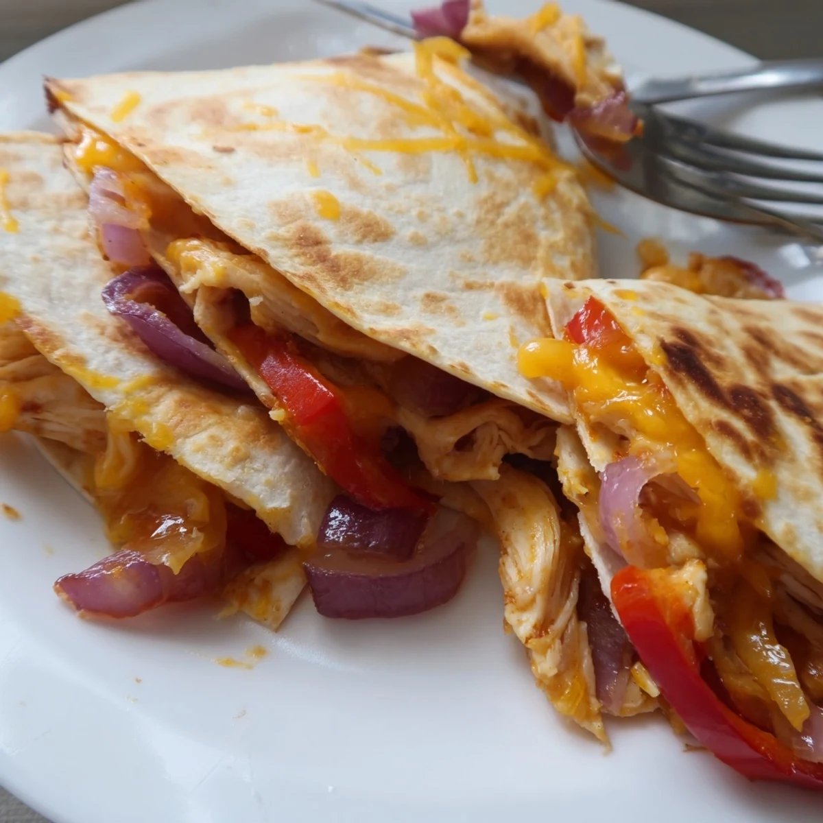 Sizzling Chicken Quesadillas with Peppers are cooked in a skillet with vibrant red and yellow bell peppers and onions.
