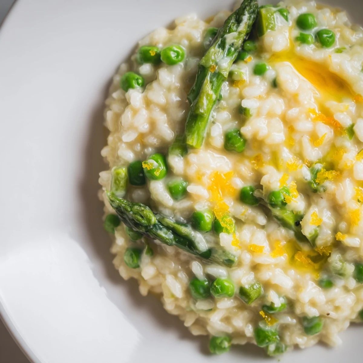 Freshly grated Parmigiano Reggiano and chives top the Creamy Spring Pea and Asparagus Risotto, ready to be served as a delicious main dish.