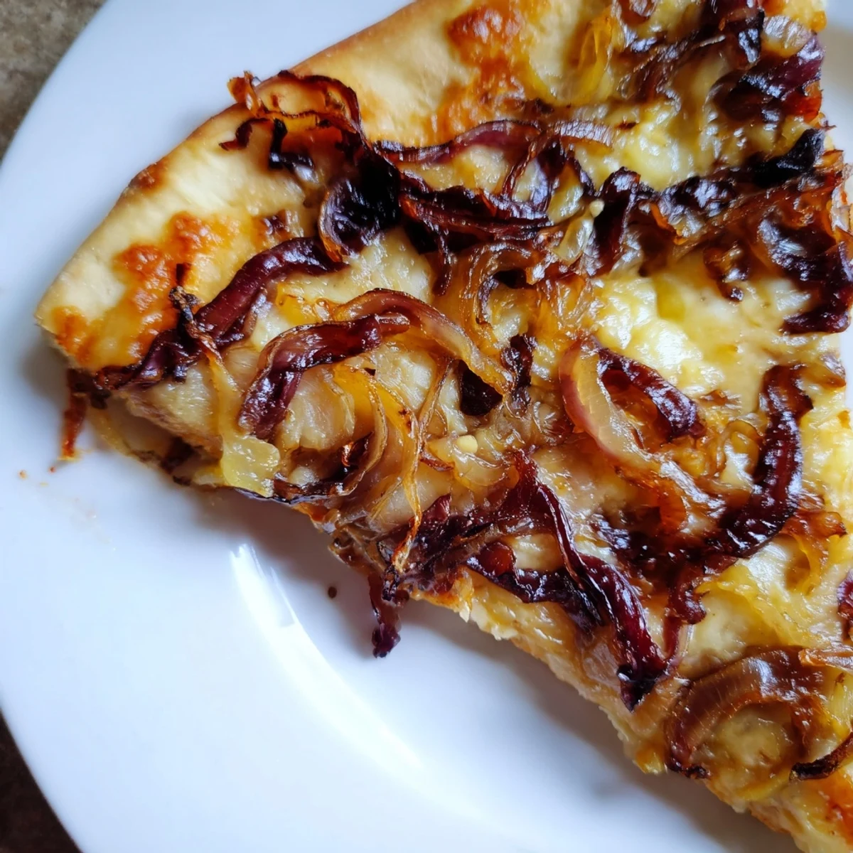 Sliced Caramelized Onion Pizza With Melty Cheese is served on a wooden board with arugula garnish.