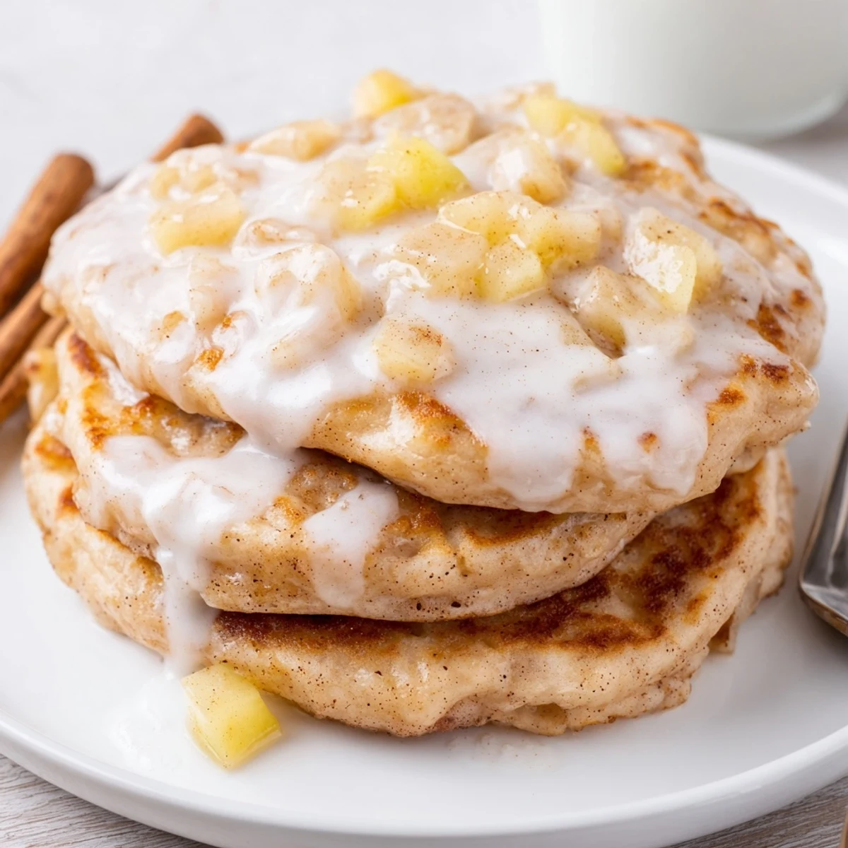 Golden-brown Apple Fritter Pancakes sizzling in a skillet, studded with tender diced apples and aromatic cinnamon.