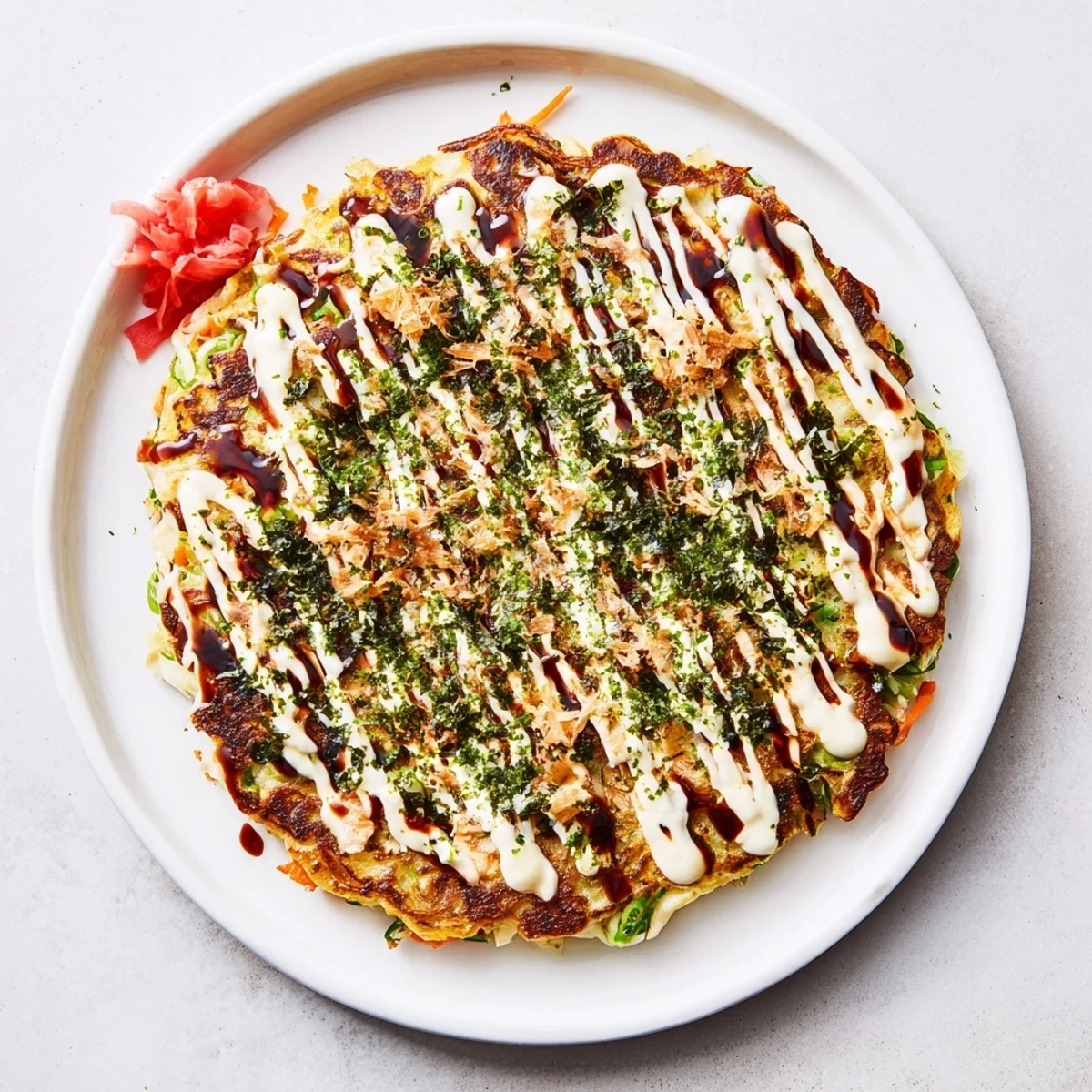 Golden-brown Chicken Okonomiyaki pancakes served hot with Japanese mayonnaise and pickled ginger for a delicious meal.