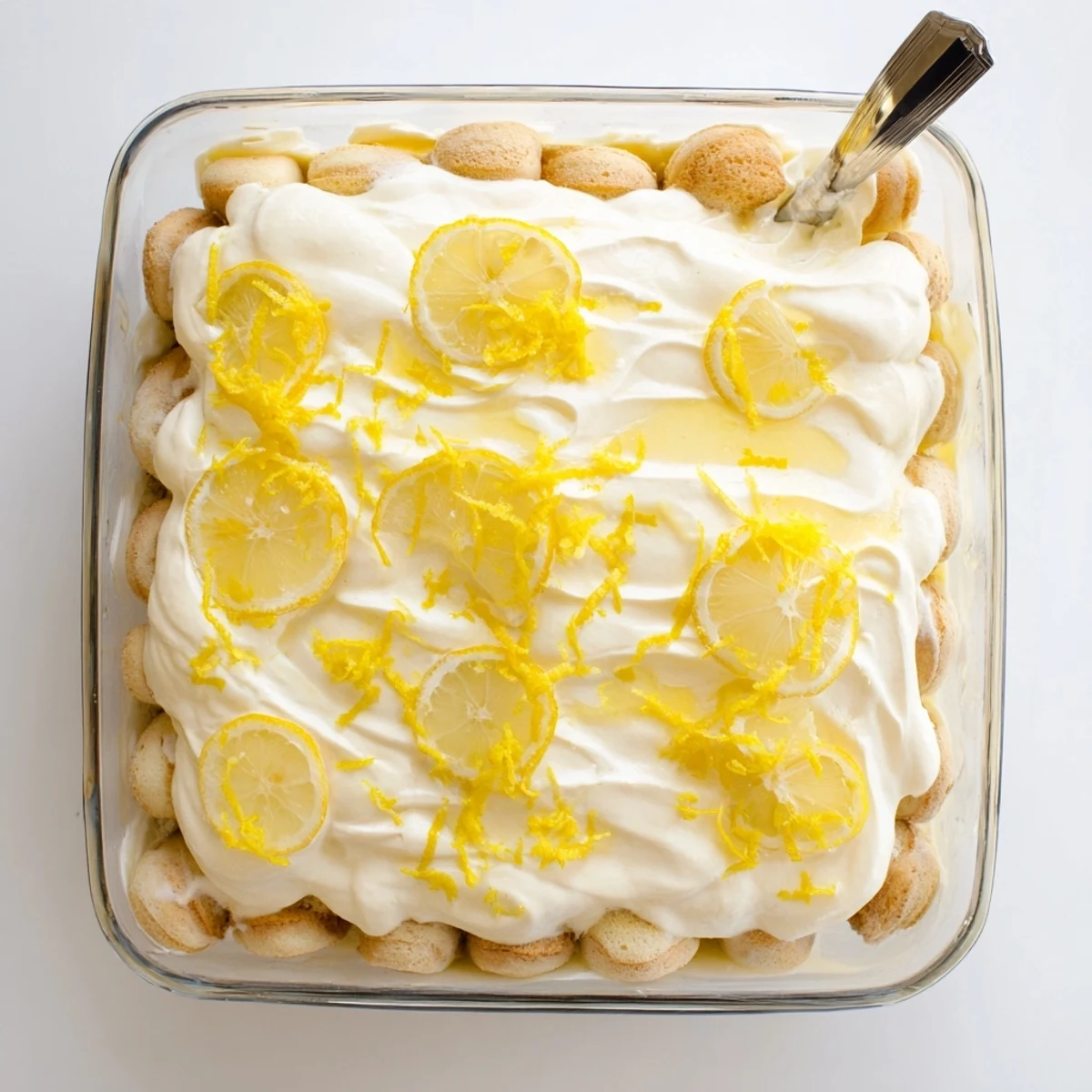 Bright layers of zesty Lemon Limoncello Italian Tiramisu featuring creamy mascarpone and lemon curd garnished with fresh zest and slices.