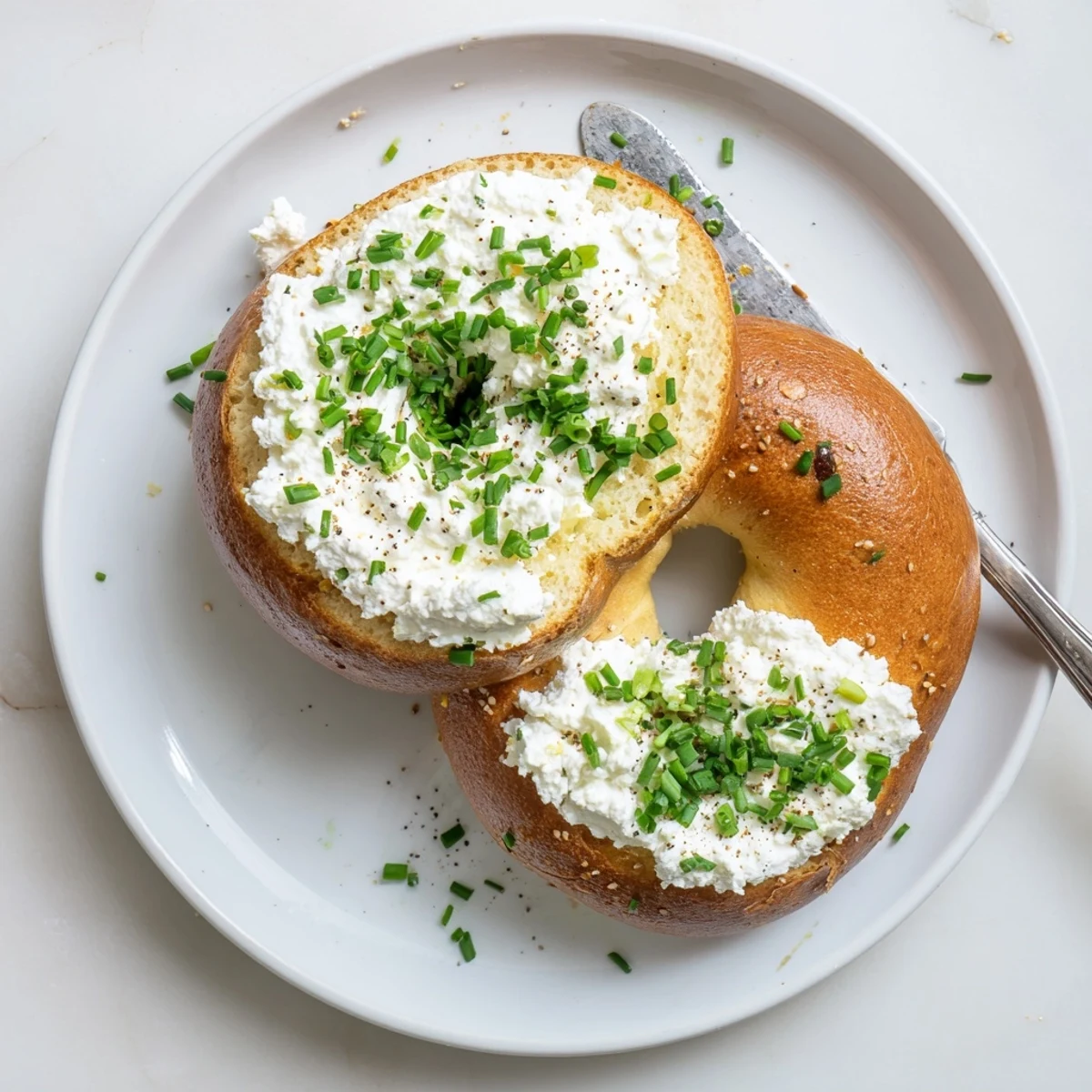 Freshly baked Protein Bagels with Cottage Cheese topped with creamy cottage cheese and chives on a rustic board.