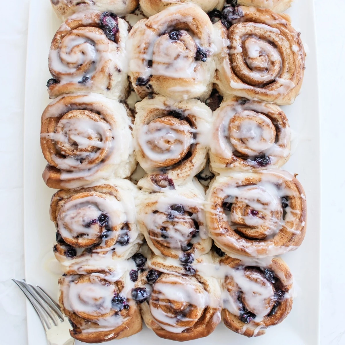 Freshly baked Blueberry Cinnamon Rolls stacked high, revealing a tender interior packed with cinnamon-sugar and blueberries.