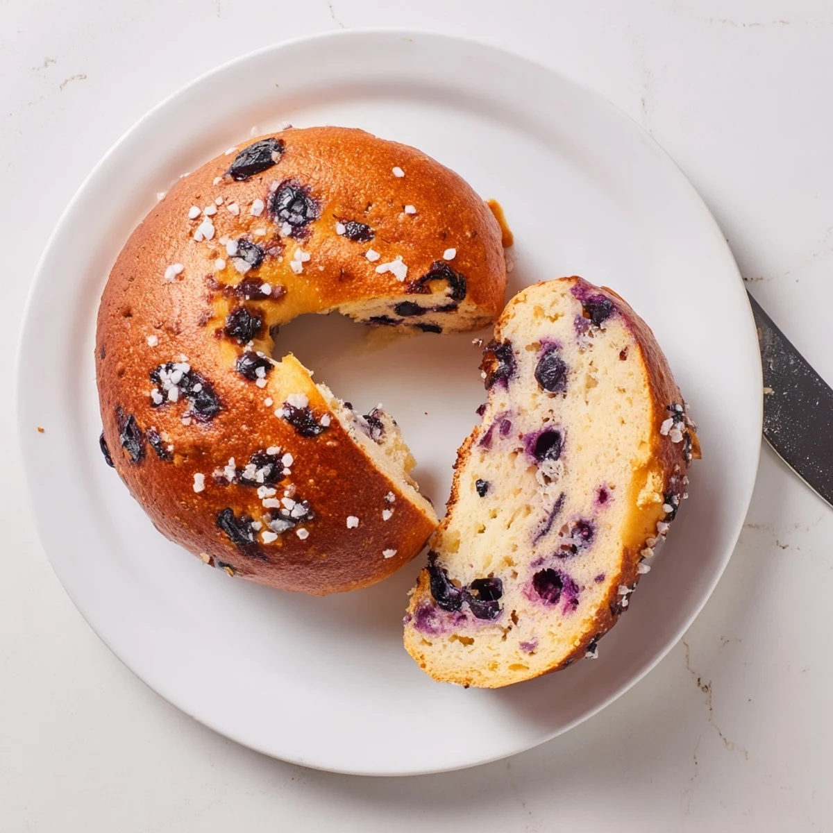 Freshly baked gluten-free blueberry bagels cooling on a wire rack, their soft crumb and sweet berry scent visible.