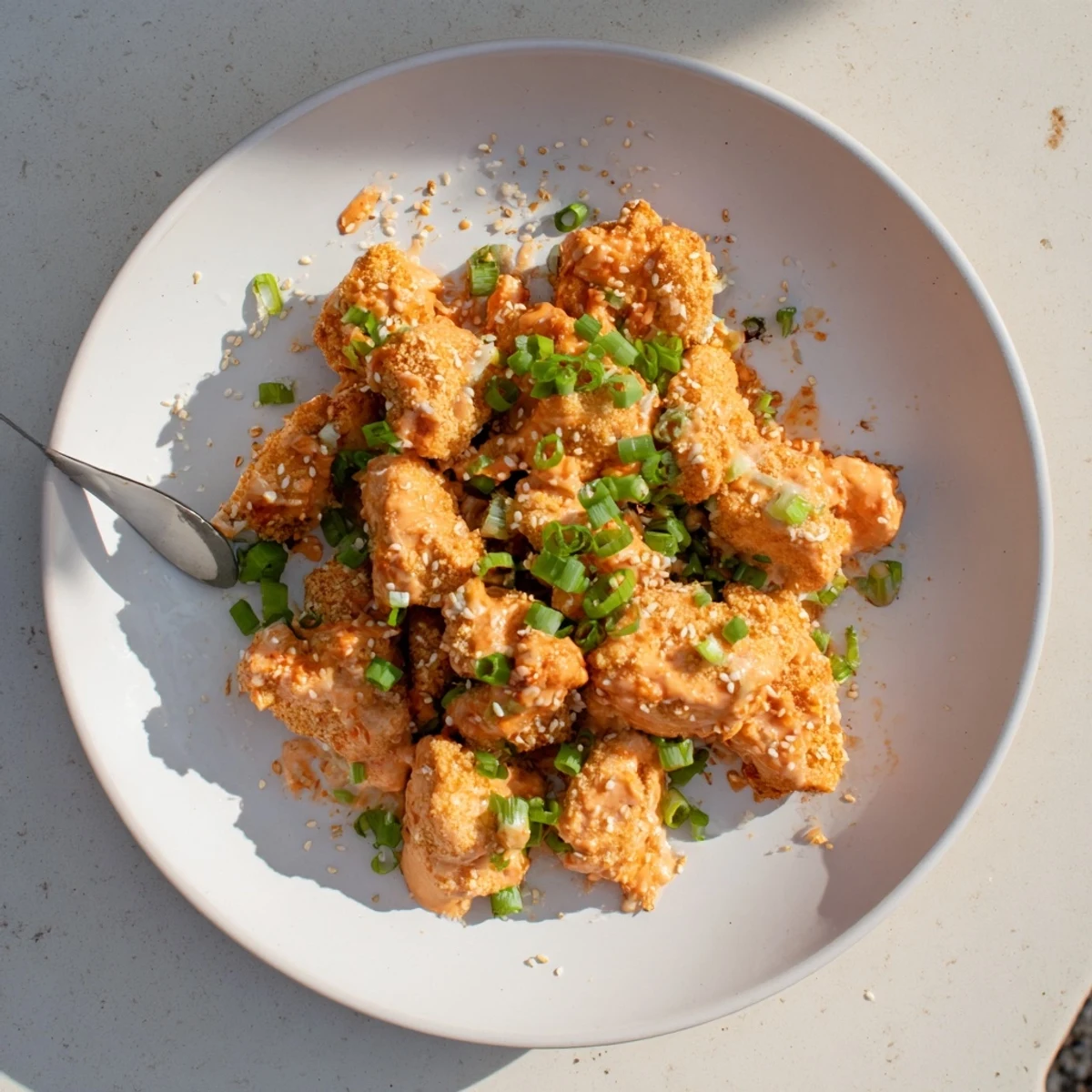 Crispy baked chicken bites coated in almond flour and parmesan, tossed in creamy bang bang sauce for a low carb dinner.