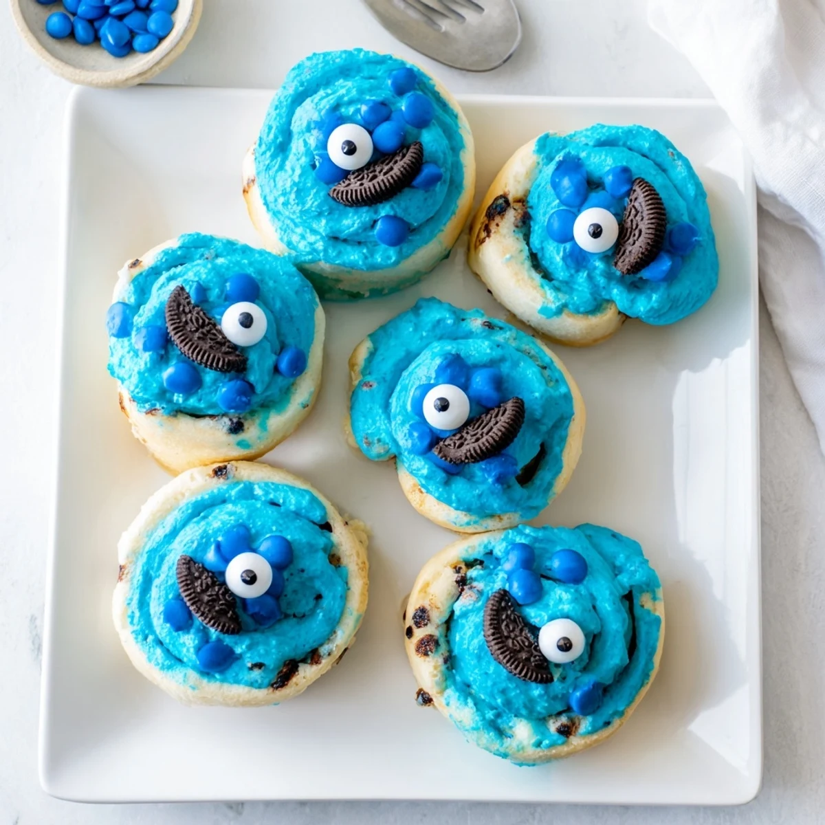 Warm blue Cookie Monster Cinnamon Rolls stuffed with cinnamon-sugar and chocolate chips, served with milk or coffee.