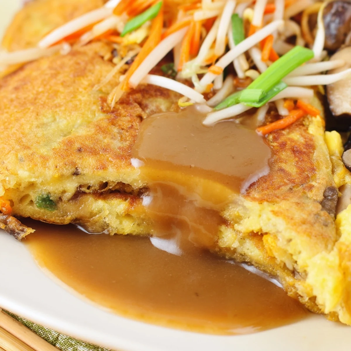 Fluffy Chinese-American Egg Foo Young omelet with vegetables and drizzled rich sauce