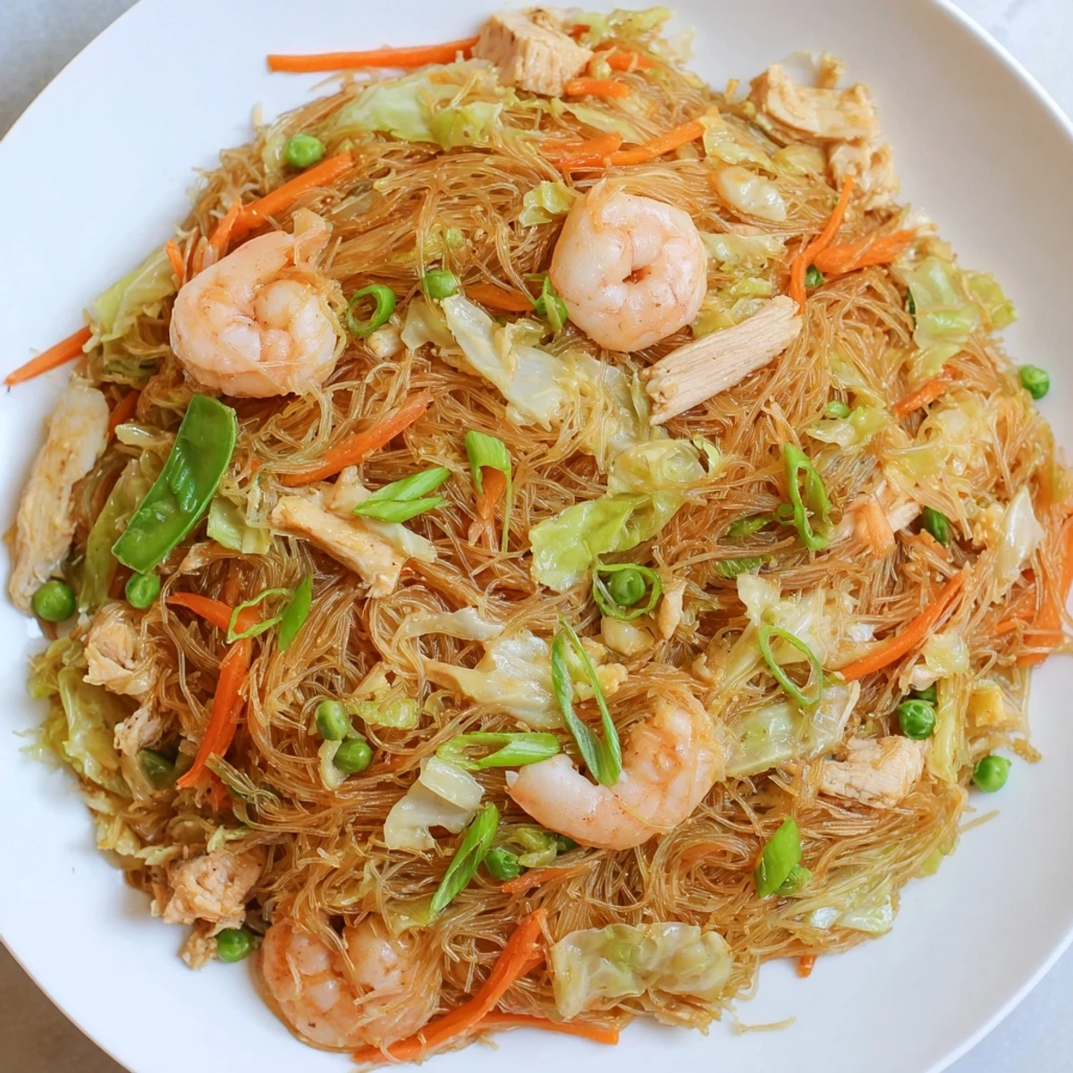 Savory Filipino Pancit Bihon featuring springy rice noodles tossed with crisp veggies and succulent seafood