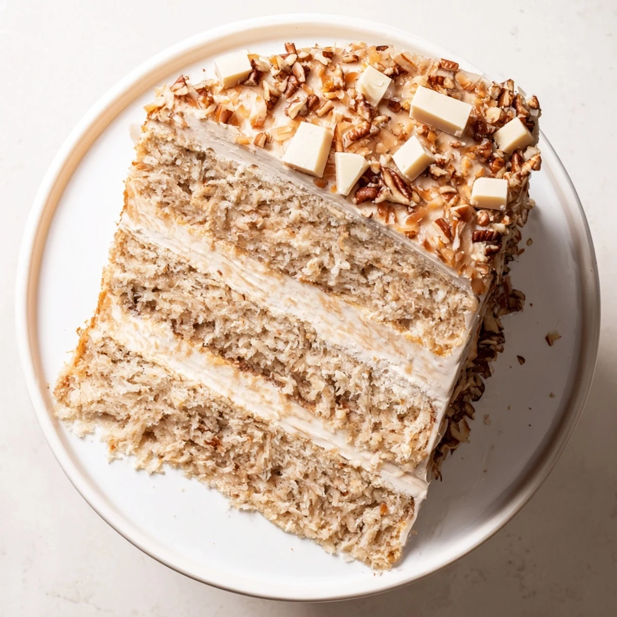 Elegant White German Chocolate Cake plated on white serving dish garnished with shredded coconut