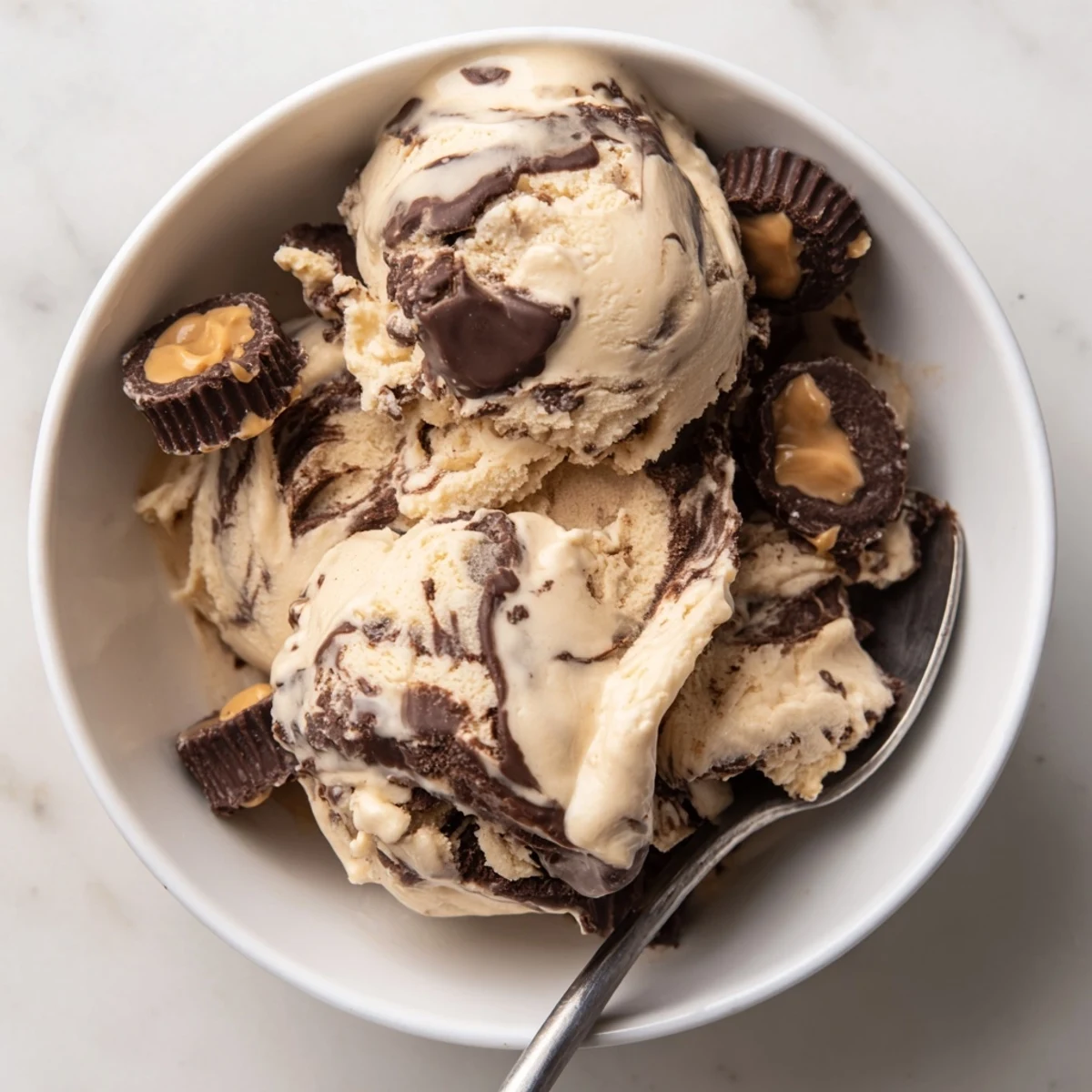 Golden scoop of Moose Tracks ice cream topped with chocolate peanut butter cups and fudge