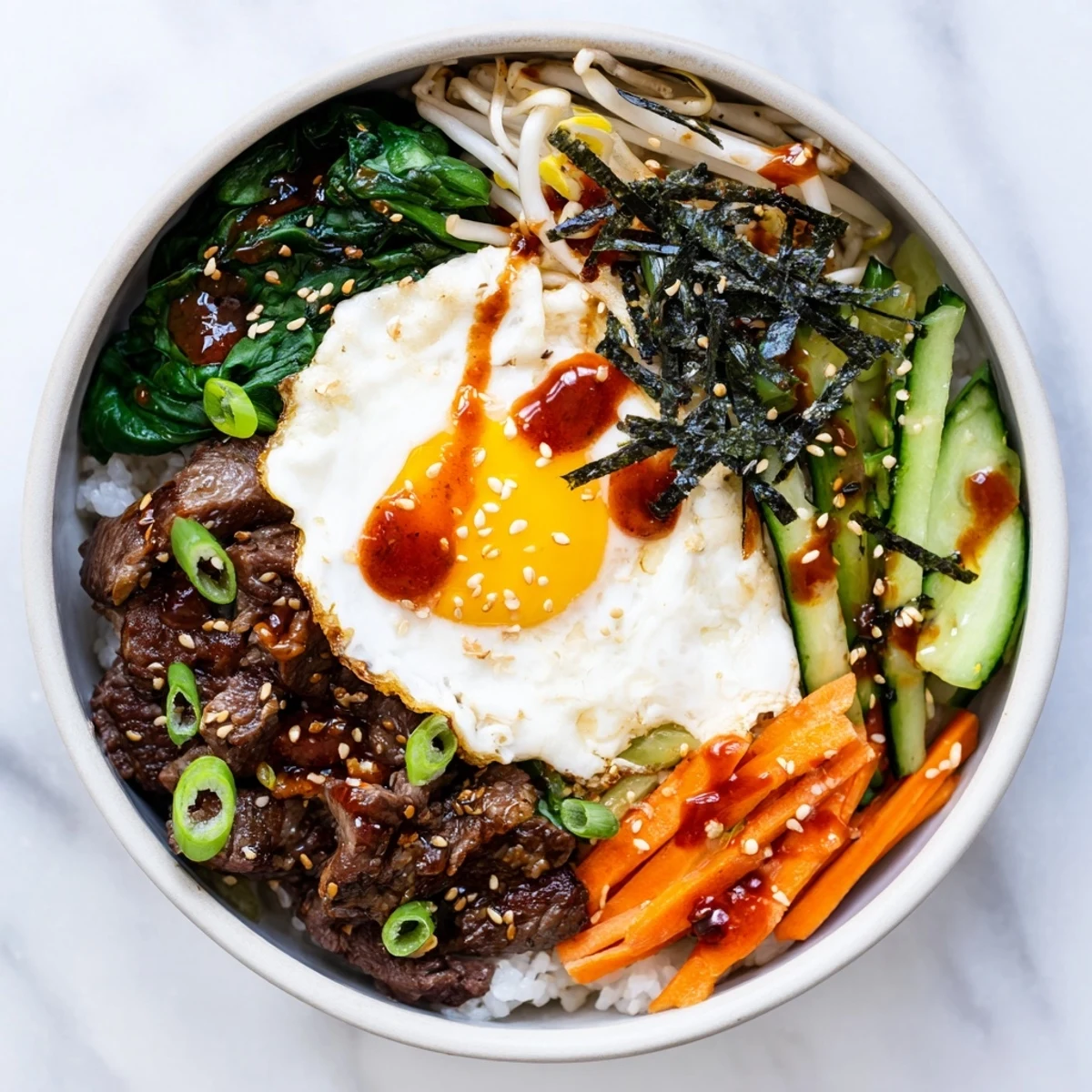 Sunny-side up egg crowns this Korean-inspired breakfast bowl with marinated beef and crisp vegetables over warm white rice drizzled with spicy gochujang sauce
