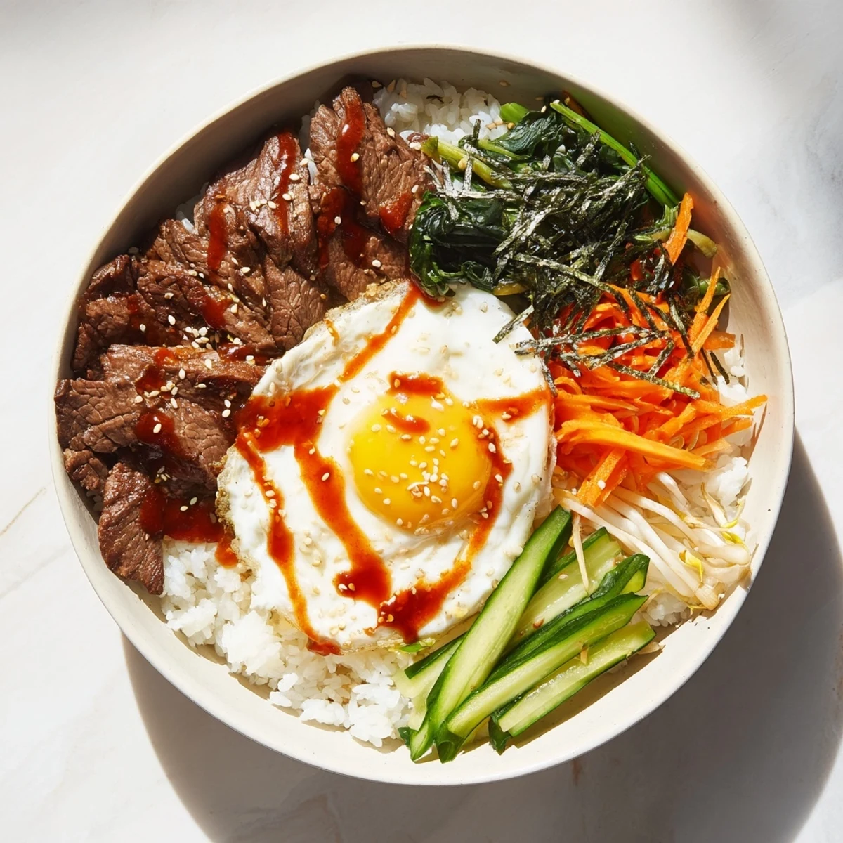 Vibrant Korean-inspired breakfast bowl arranged with savory beef slices fresh spinach julienned carrots cucumber bean sprouts and runny fried egg