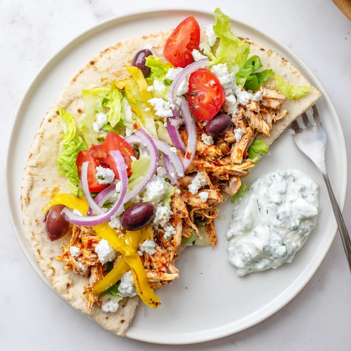 Slow cooker Greek chicken piled into warm pita bread with fresh lettuce and tangy tzatziki