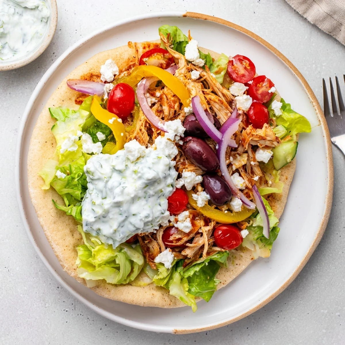 Crockpot Greek chicken pitas loaded with vegetables feta cheese and homemade tzatziki sauce