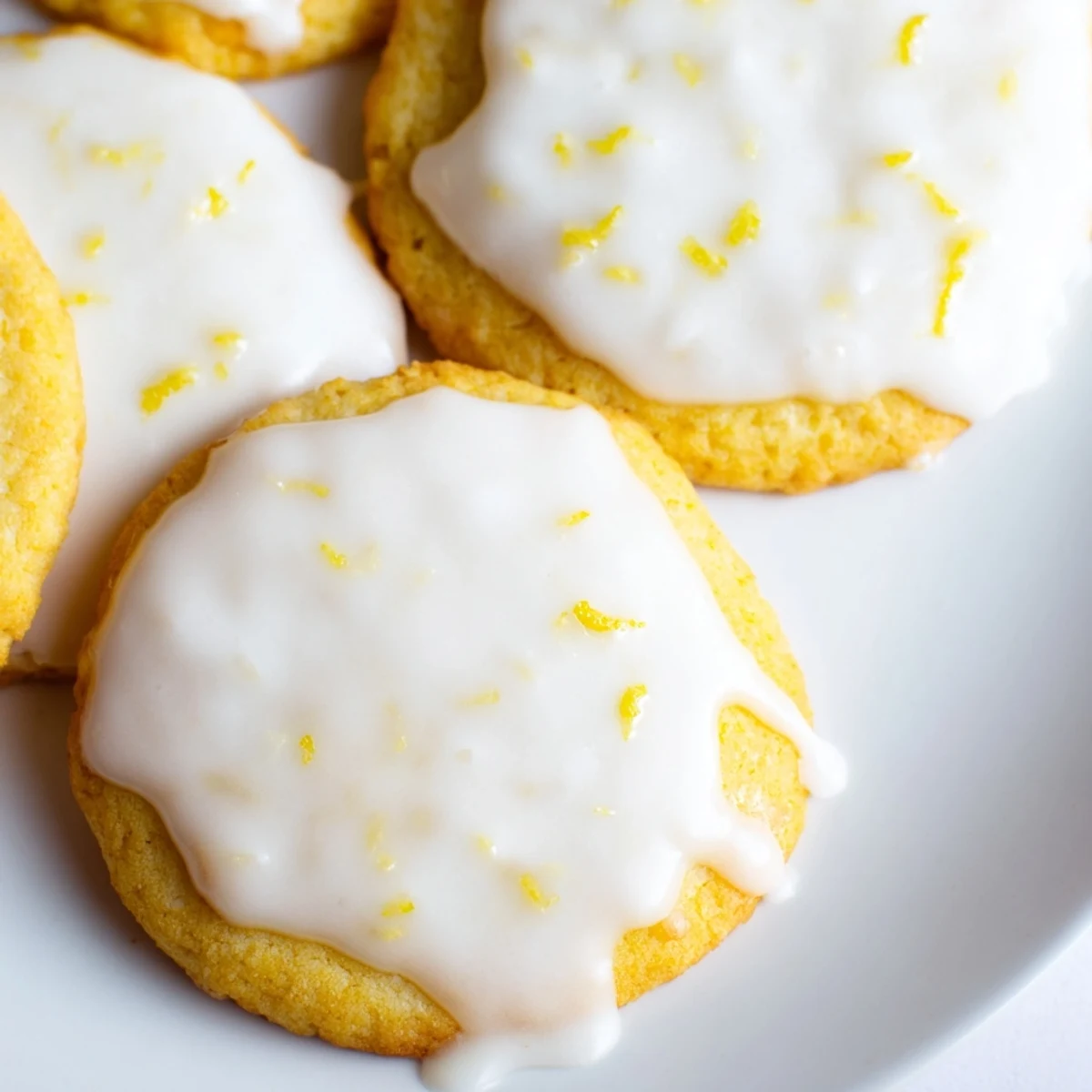 Stack of bright lemon glazed cookies with smooth white icing and golden baked edges