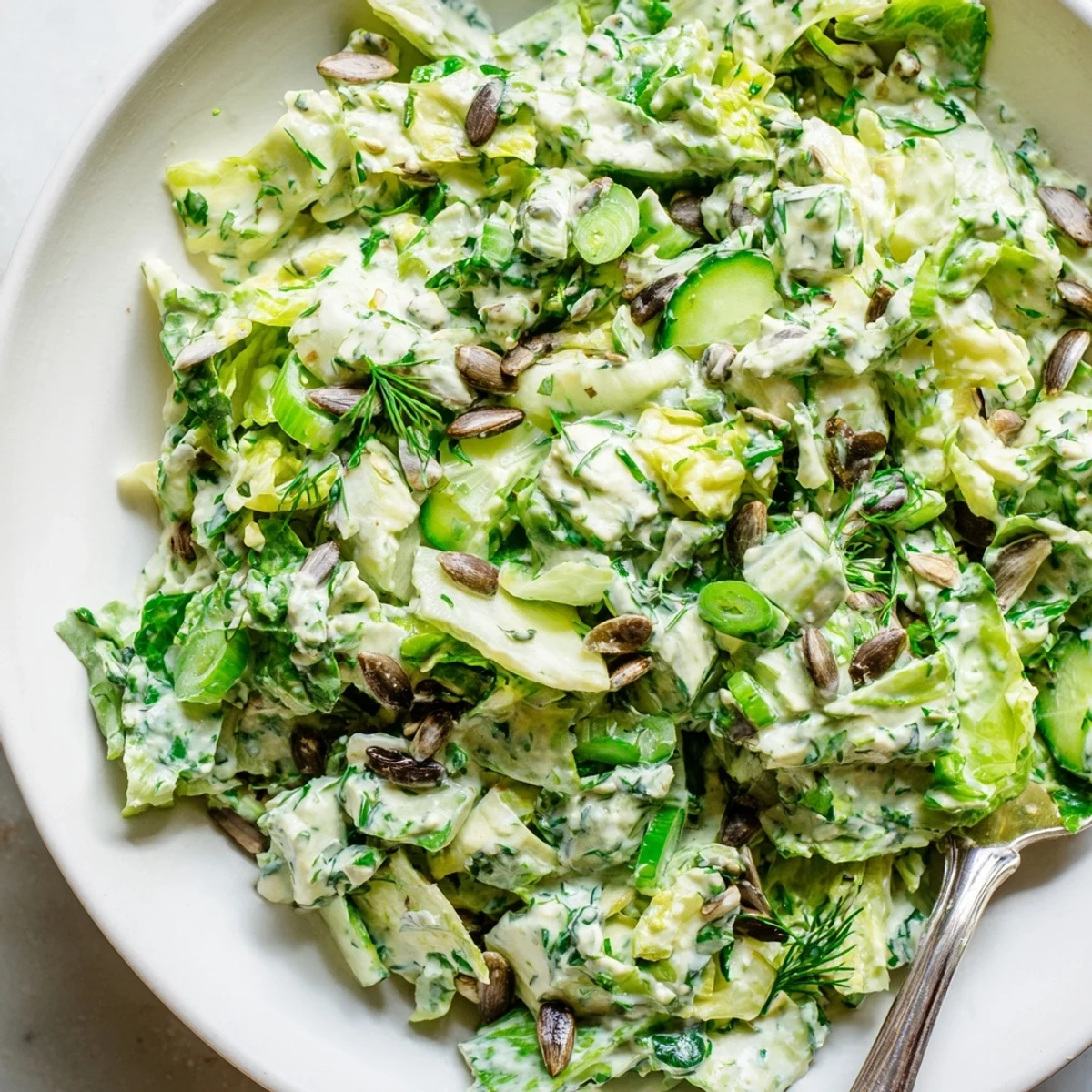Colorful Green Goddess Salad bowl topped with creamy herbed dressing and crunchy roasted seeds