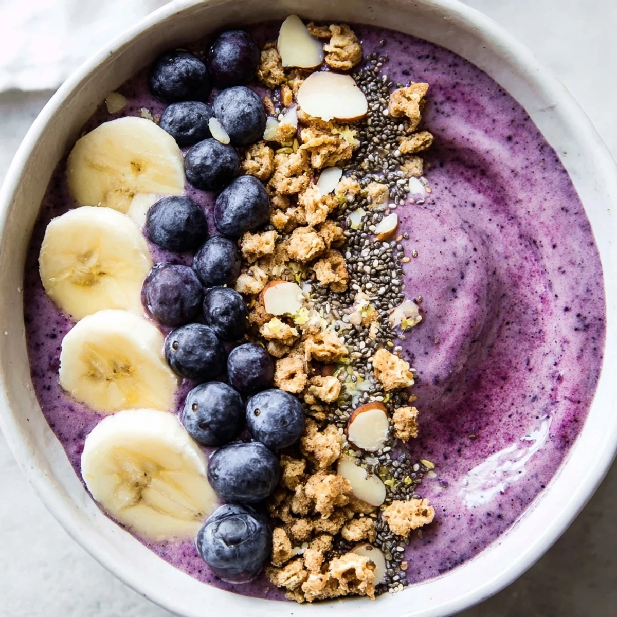Creamy blueberry smoothie bowl with Greek yogurt topped with fresh berries, granola, and coconut flakes