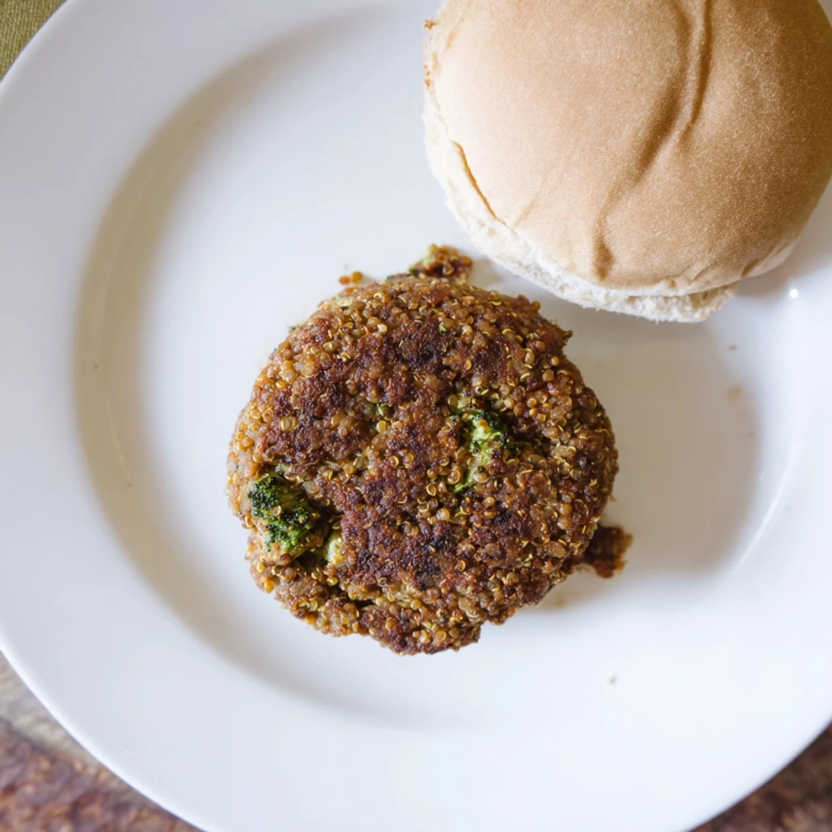 Homemade turkey broccoli and quinoa burgers sizzling in a skillet with golden brown edges and herbs