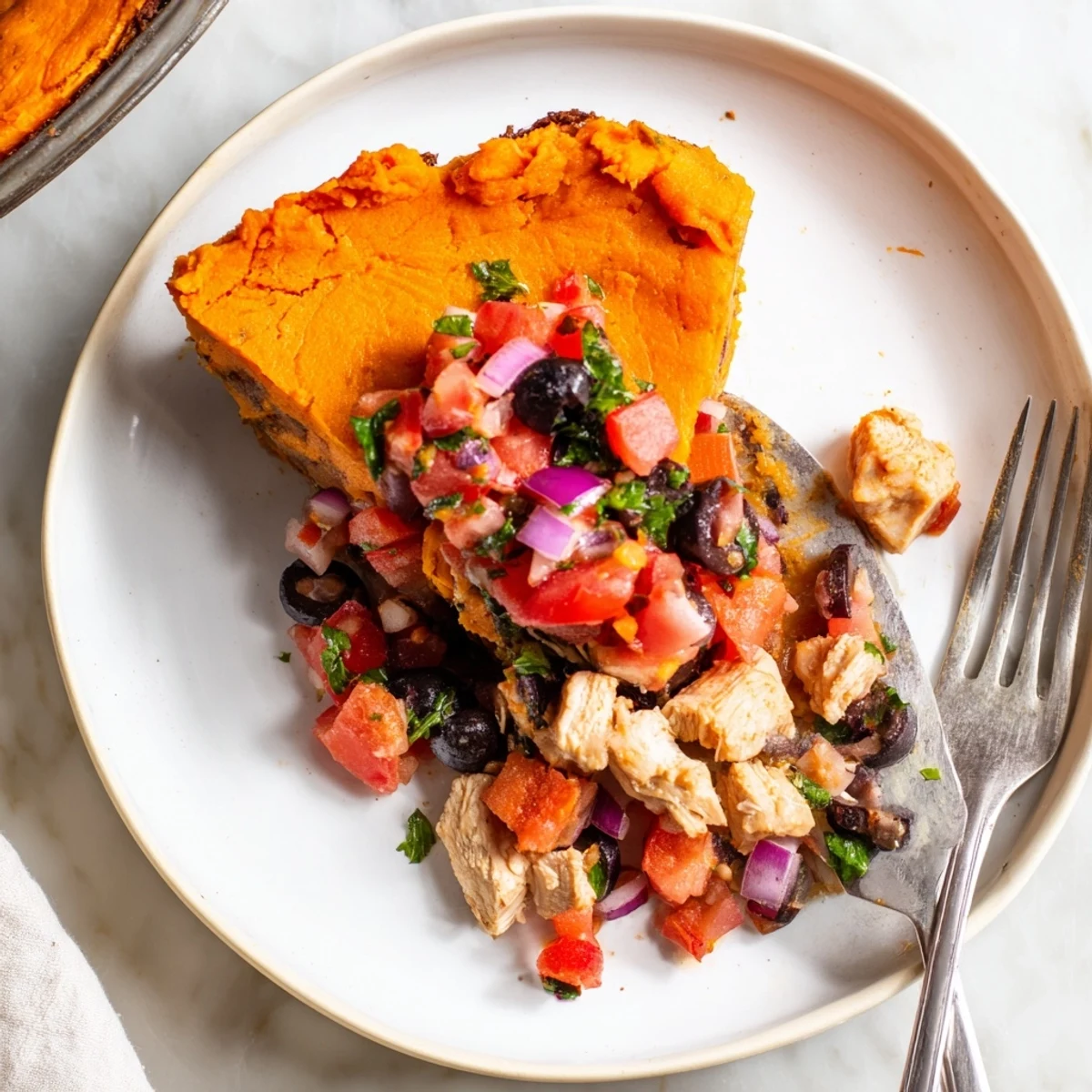 Flaky crust covers tender sweet potato chicken pie garnished with fresh Mediterranean tomato olive salsa