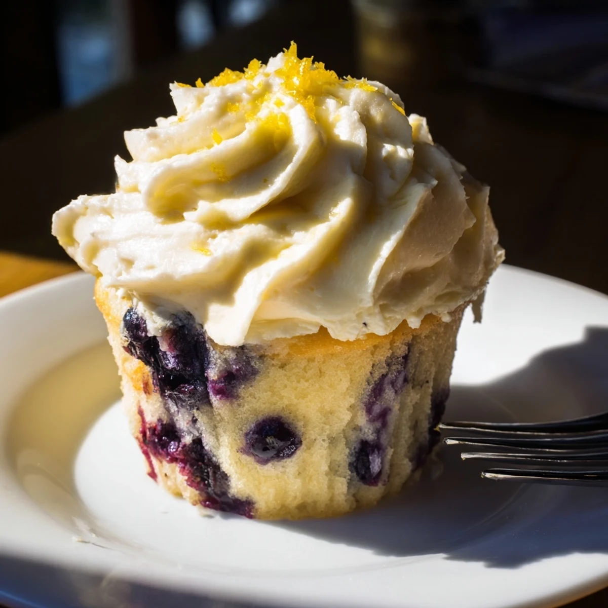 Golden homemade lemon blueberry cupcakes with tangy cream cheese frosting on a white serving plate