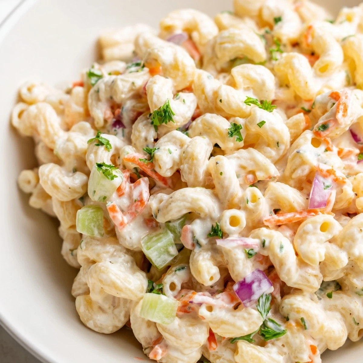 Colorful bowl of tangy and creamy macaroni salad loaded with crunchy red bell peppers and diced celery