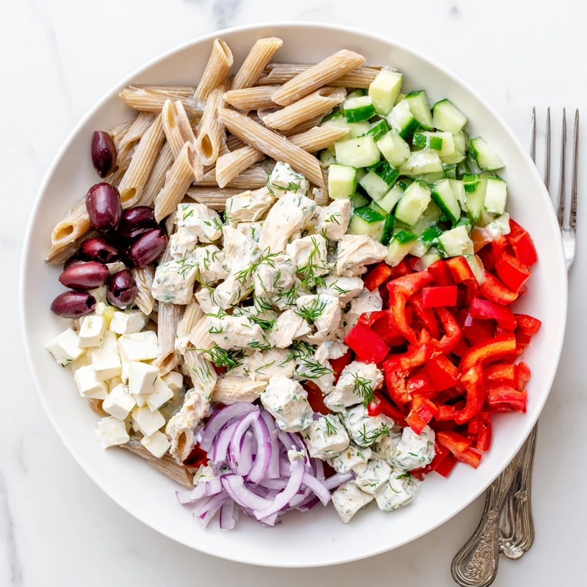 Colorful high protein Greek pasta salad loaded with juicy tomatoes, crisp cucumber, and feta cheese