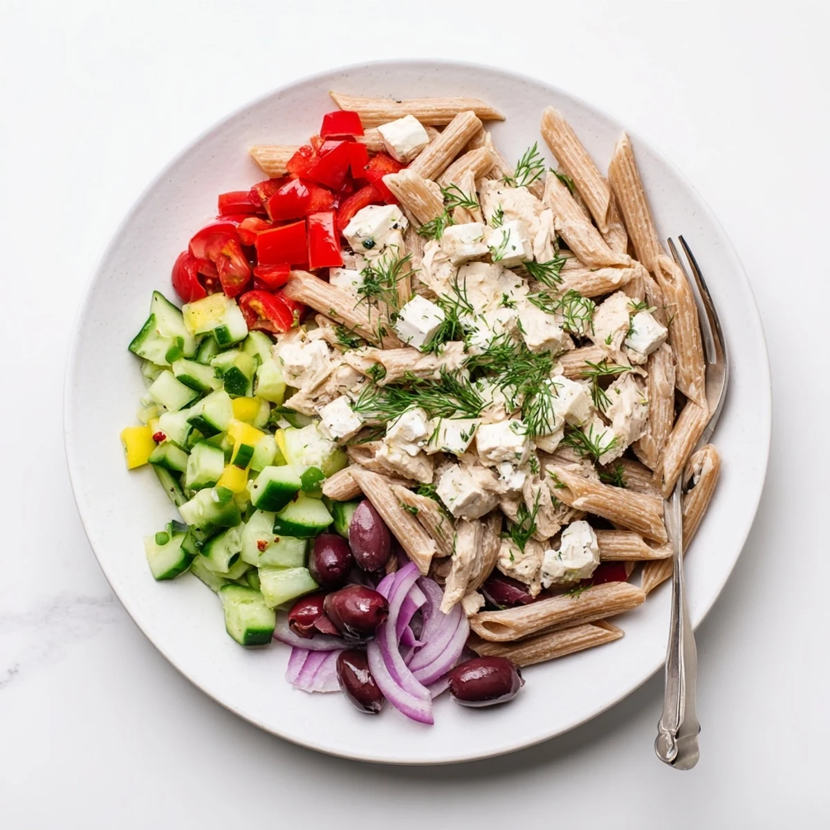 Creamy high protein Greek pasta salad in a rustic bowl with Kalamata olives and peppers