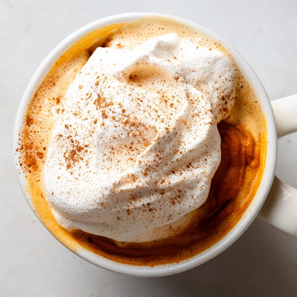 Creamy homemade pumpkin spice latte topped with whipped cream and cinnamon dust