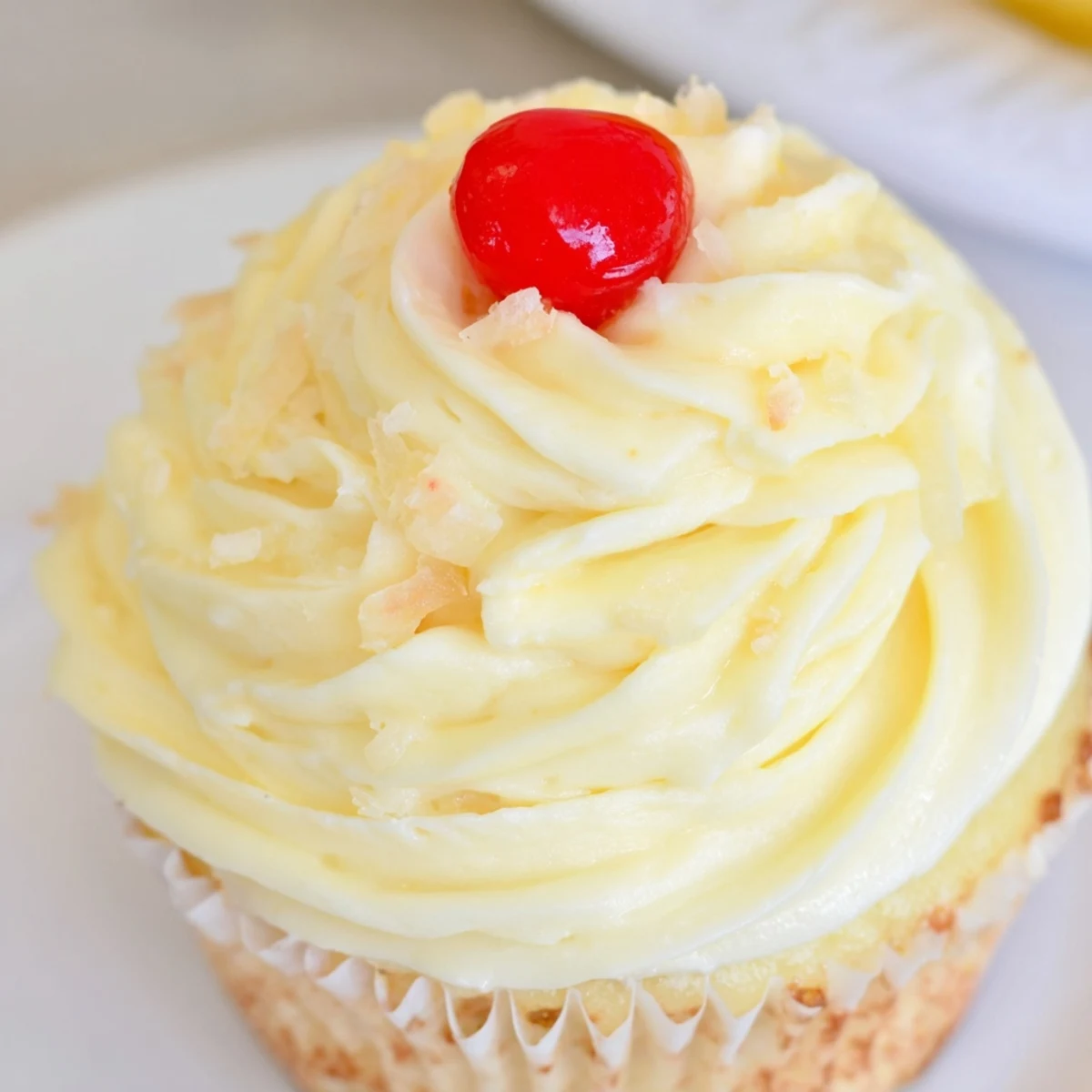 Golden Dole Whip Cupcakes topped with fluffy pineapple whipped frosting and cherry garnish