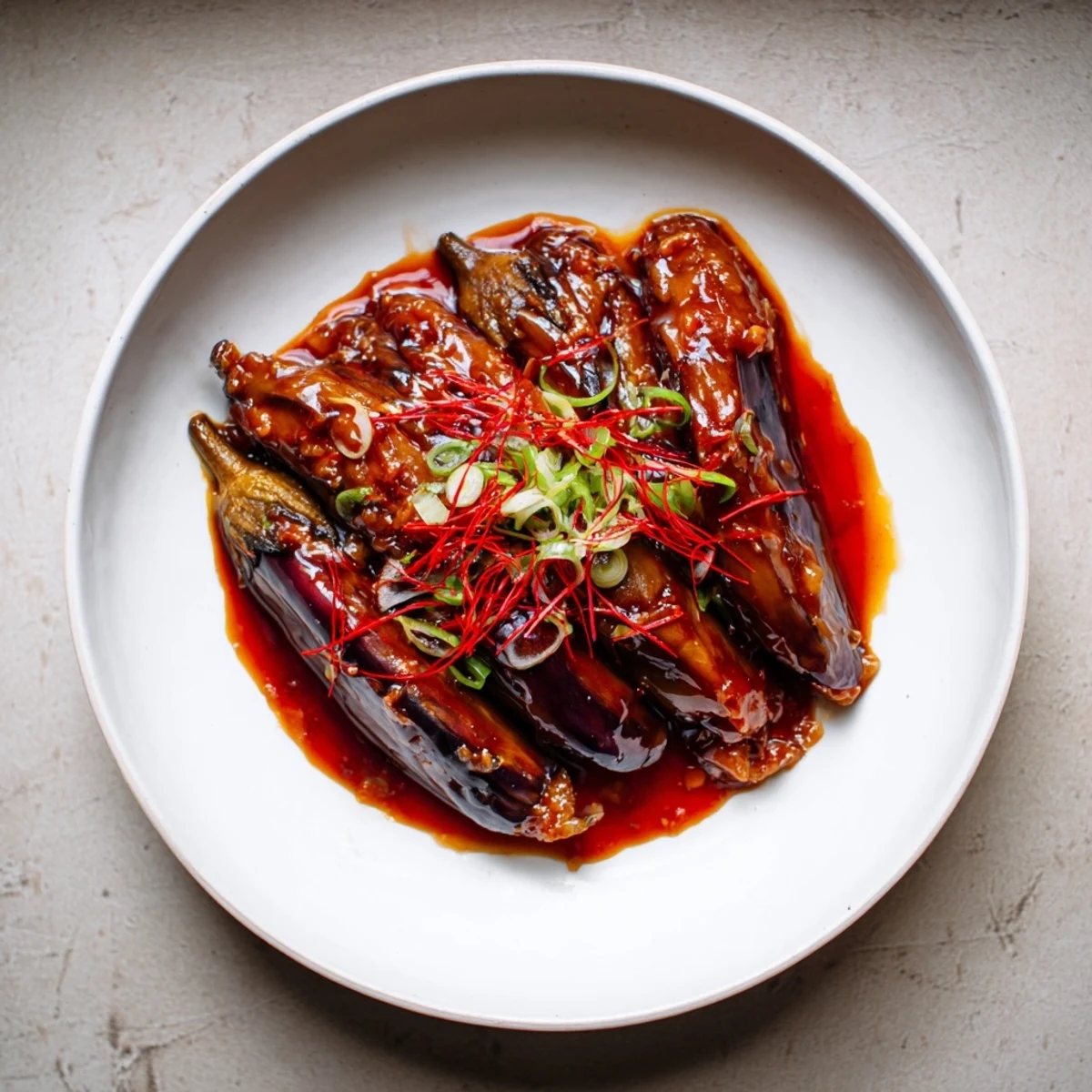 Sichuan Style Braised Aubergines glistening in spicy red sauce over steamed rice