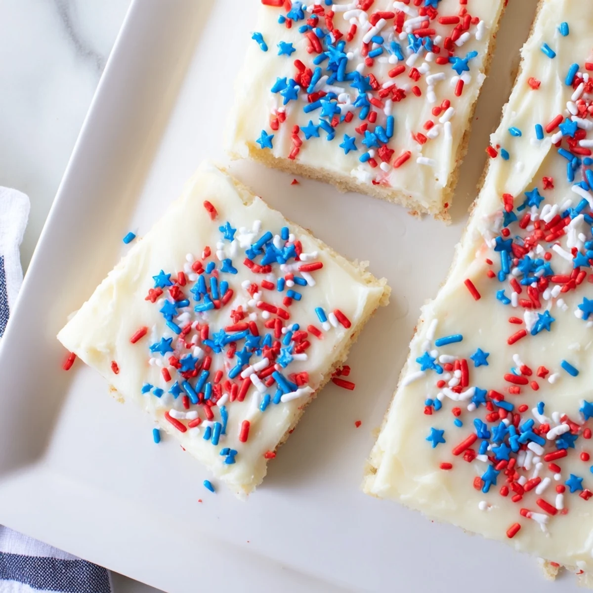 Soft baked 4th of July sugar cookie bars topped with creamy vanilla frosting and festive red white blue sprinkles for Independence Day