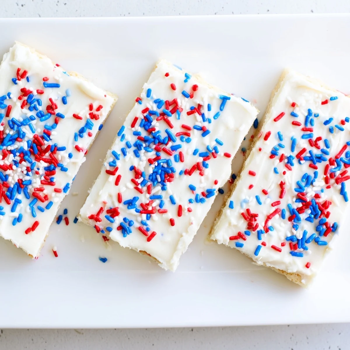 Patriotic sugar cookie bars spread with smooth buttercream and decorated with colorful sprinkles perfect for summer Fourth of July celebrations
