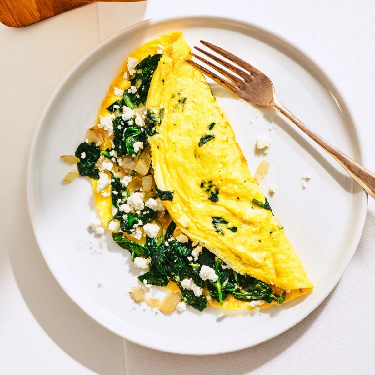 Fluffy Mediterranean spinach feta omelet recipe with melted cheese and tender wilted greens