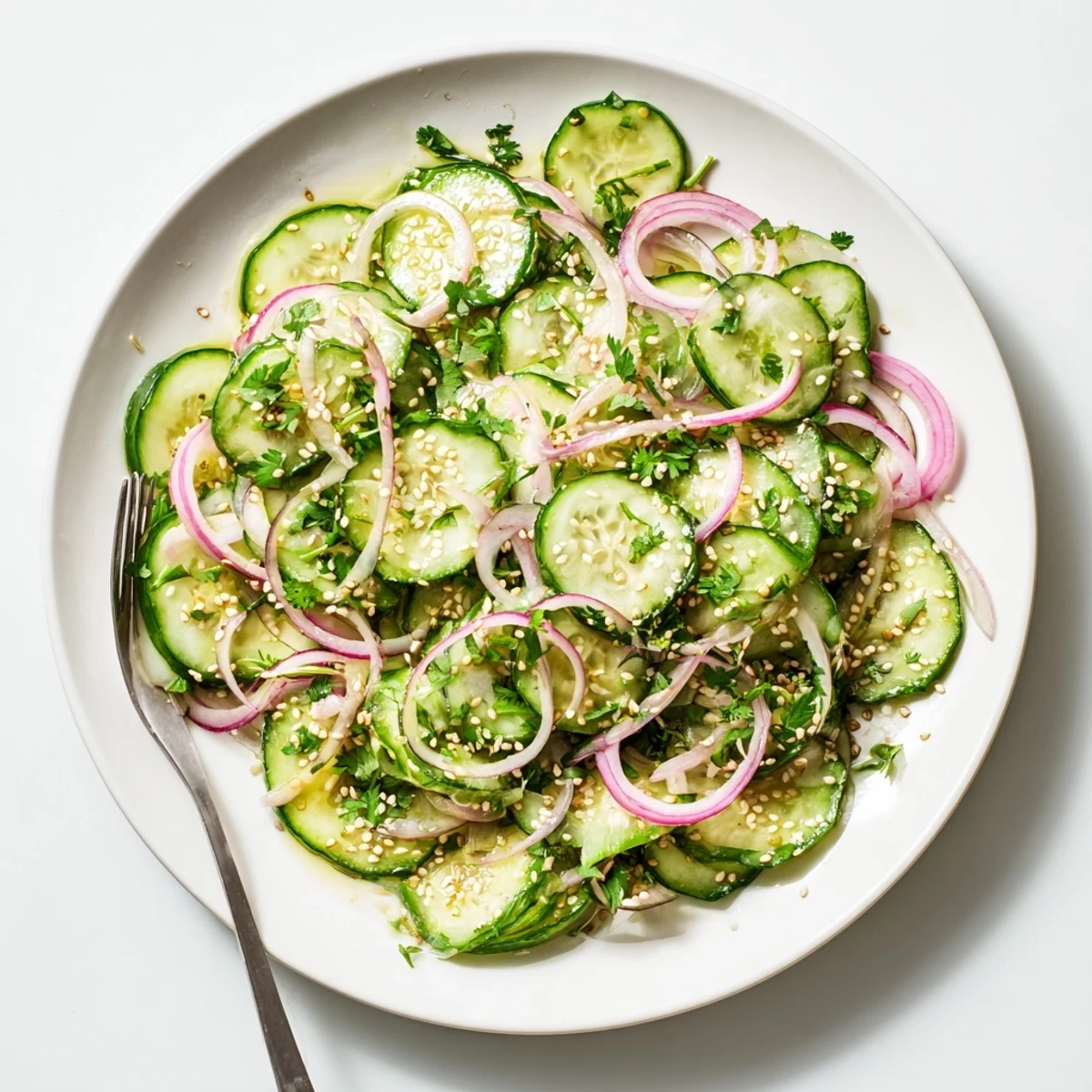 Glass bowl overflowing with honey lime cucumber salad topped with cilantro and red onion