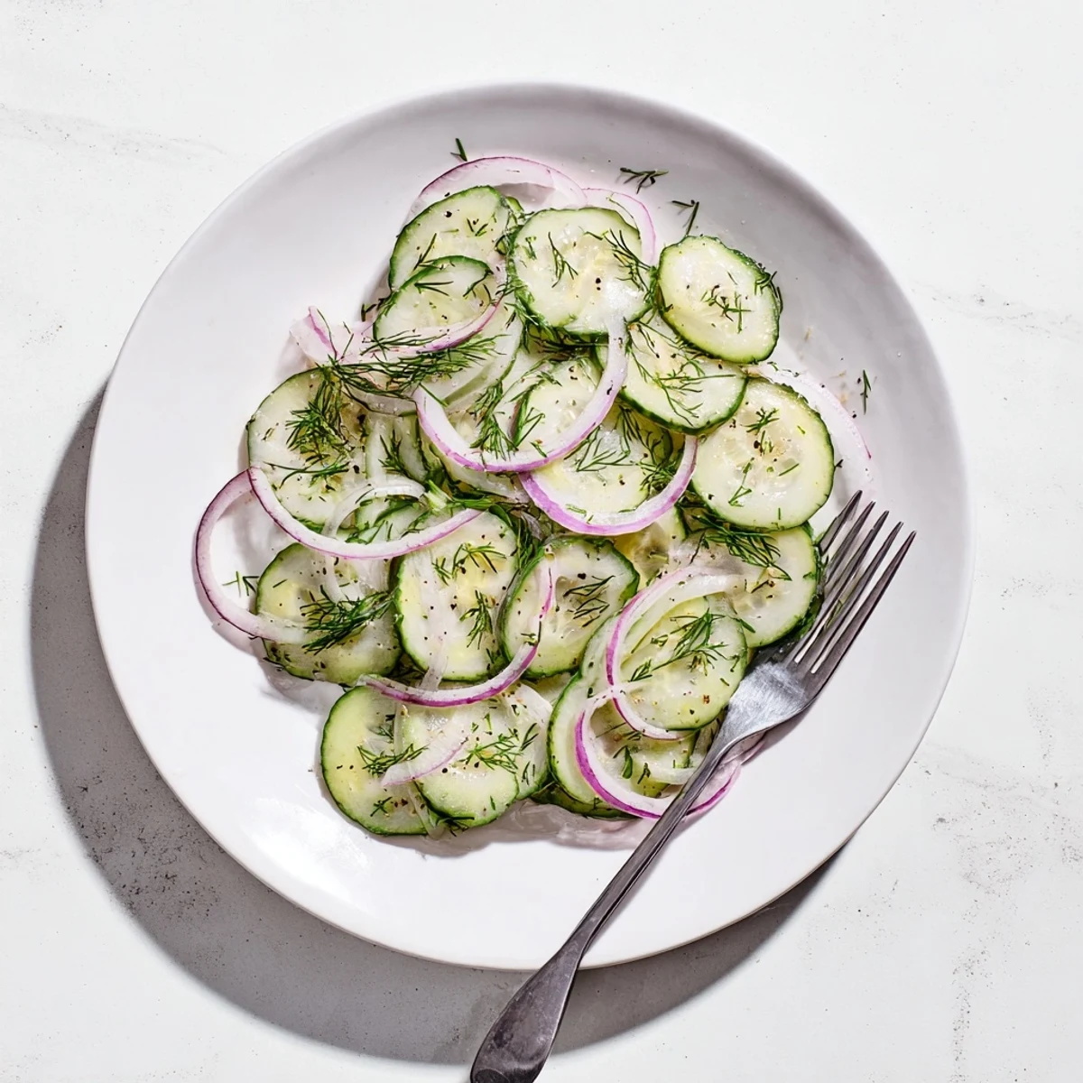 Fresh cucumber salad with thinly sliced red onions and chopped dill tossed in tangy vinaigrette
