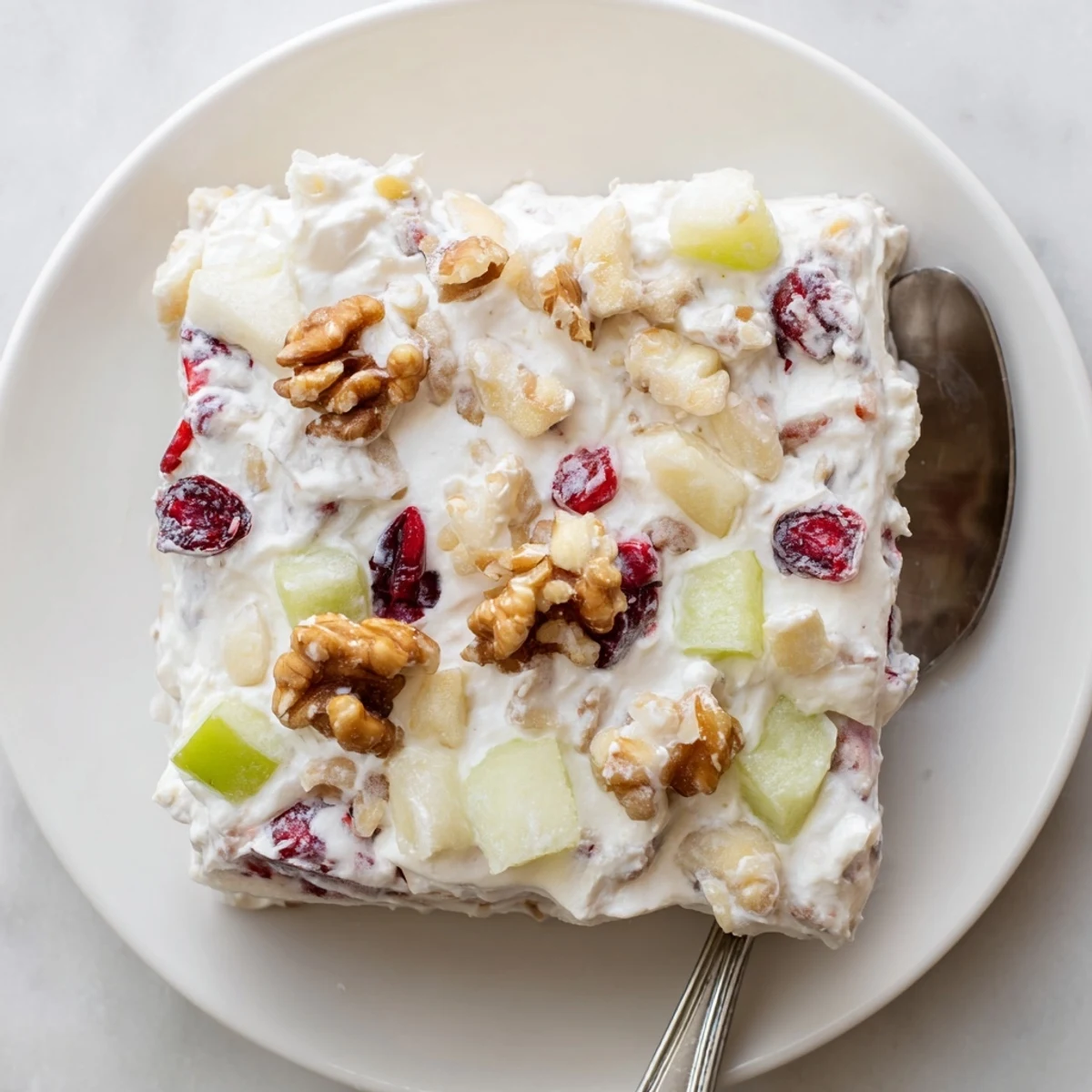 Creamy frozen cranberry salad mold garnished with fresh mint leaves, ready to serve at holiday gatherings