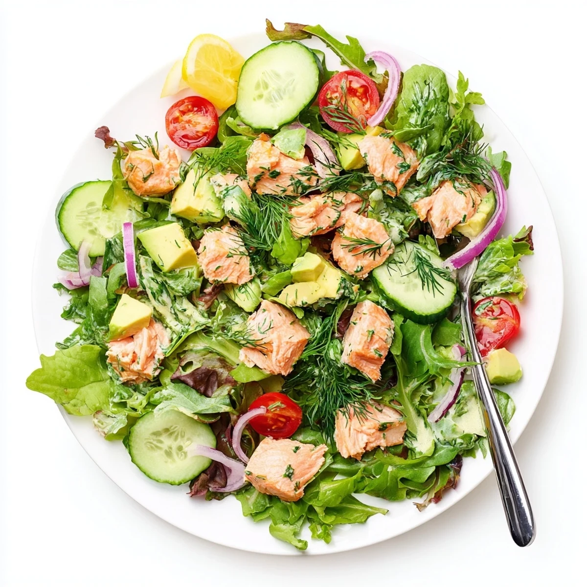 Flaky baked salmon chunks atop mixed greens with cherry tomatoes, avocado, and cucumber drizzled with lemon-dill dressing