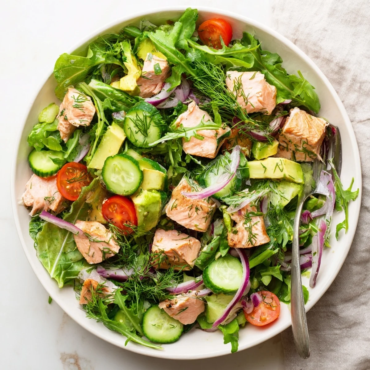 Protein-packed ultimate salmon salad with fresh dill, arugula, ripe avocado, and juicy tomatoes finished with tangy lemon vinaigrette