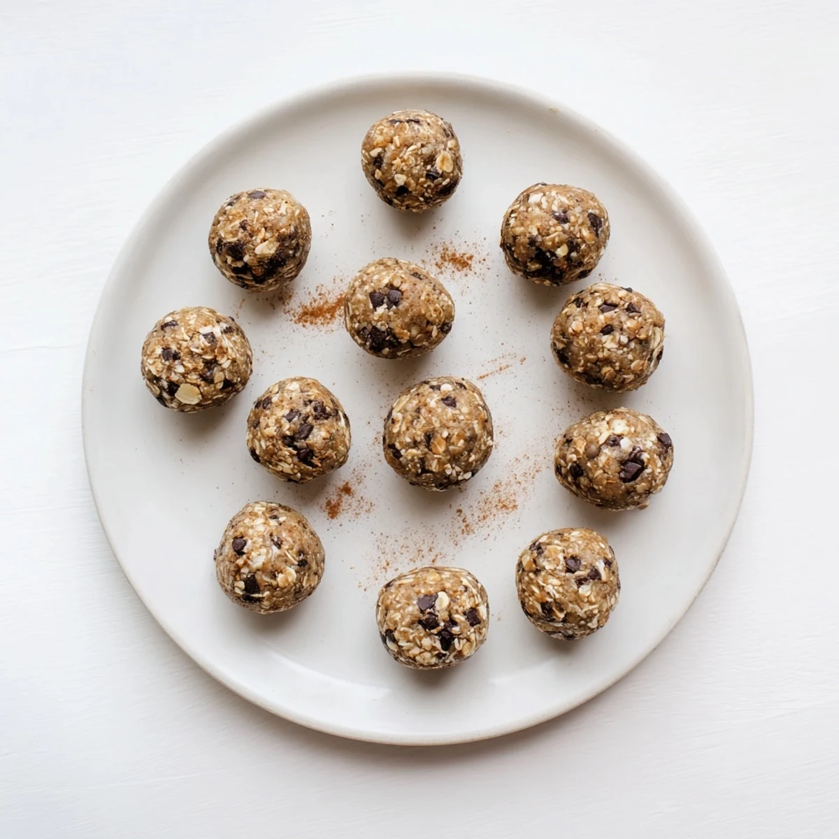 Golden brown banana bread energy balls rolled with oats and dark chocolate chips on a white plate