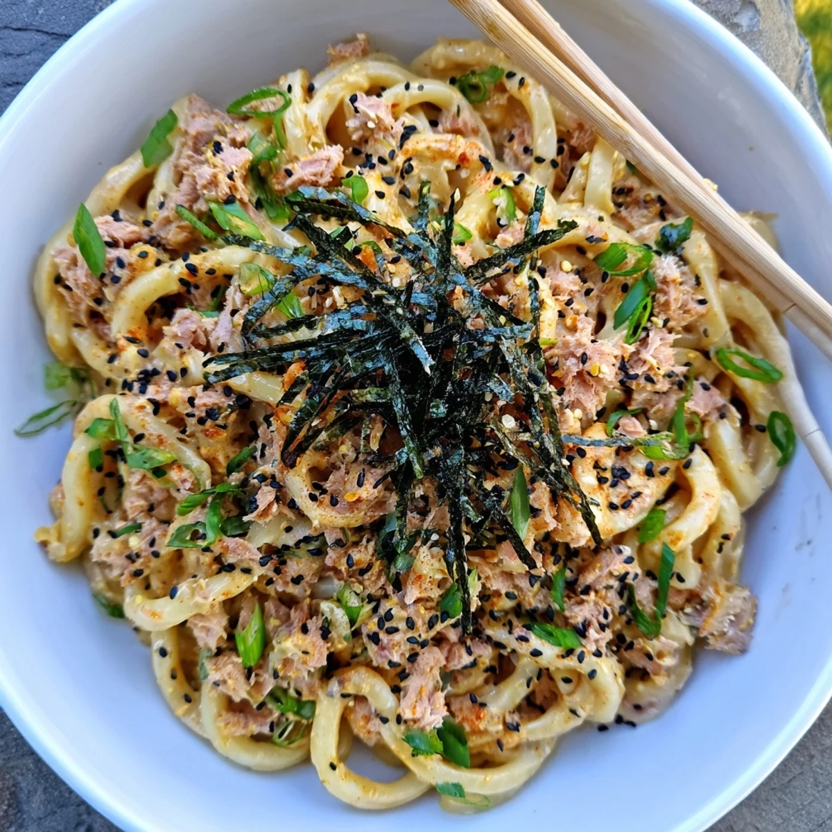 Thick chewy udon noodles tossed with creamy spicy tuna sauce and fresh garnishes