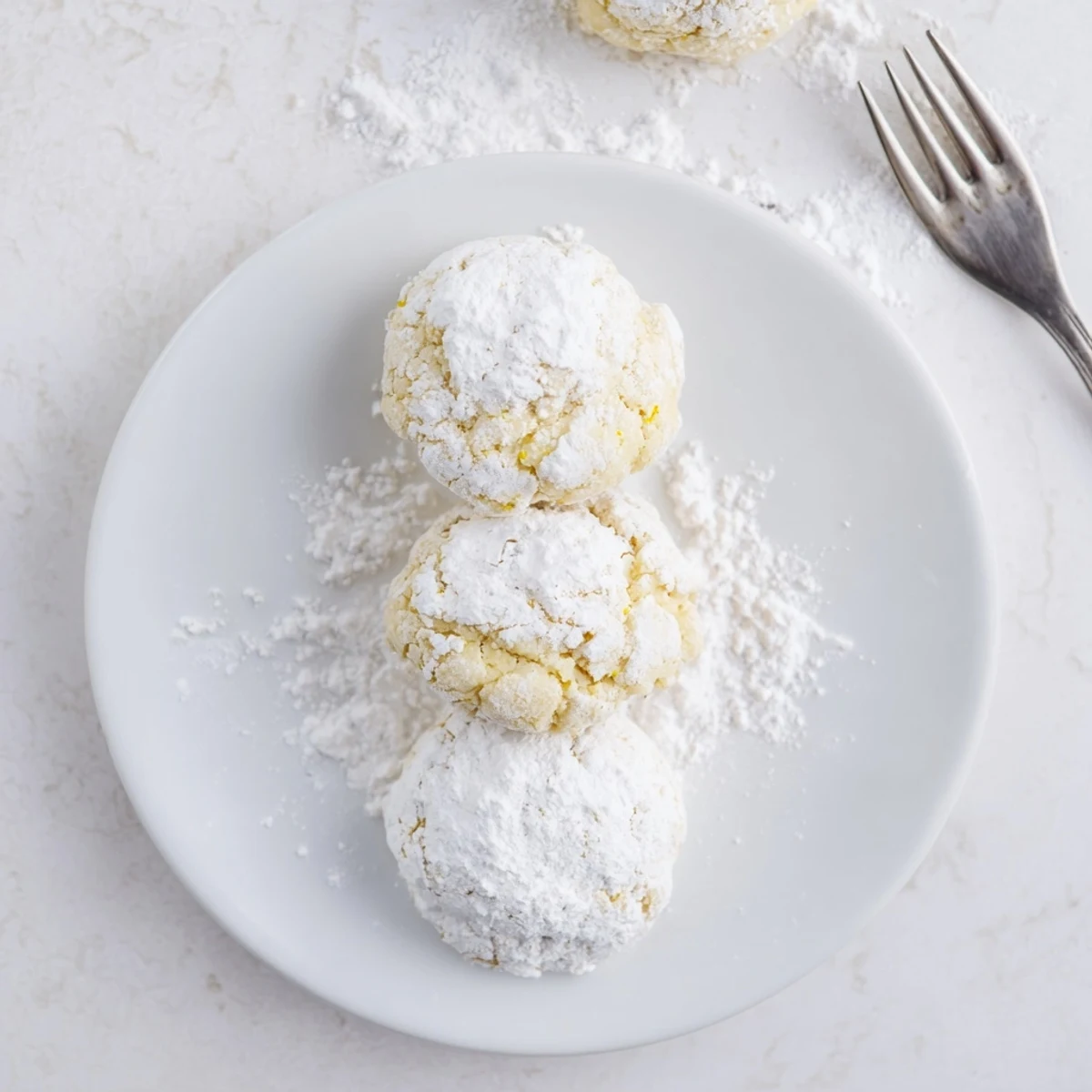 Soft lemon pixie cookies coated in white powdered sugar on a wire cooling rack