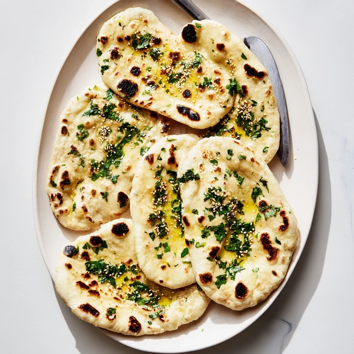 Golden brown sourdough discard soft naan brushed with melted butter and garnished with fresh cilantro
