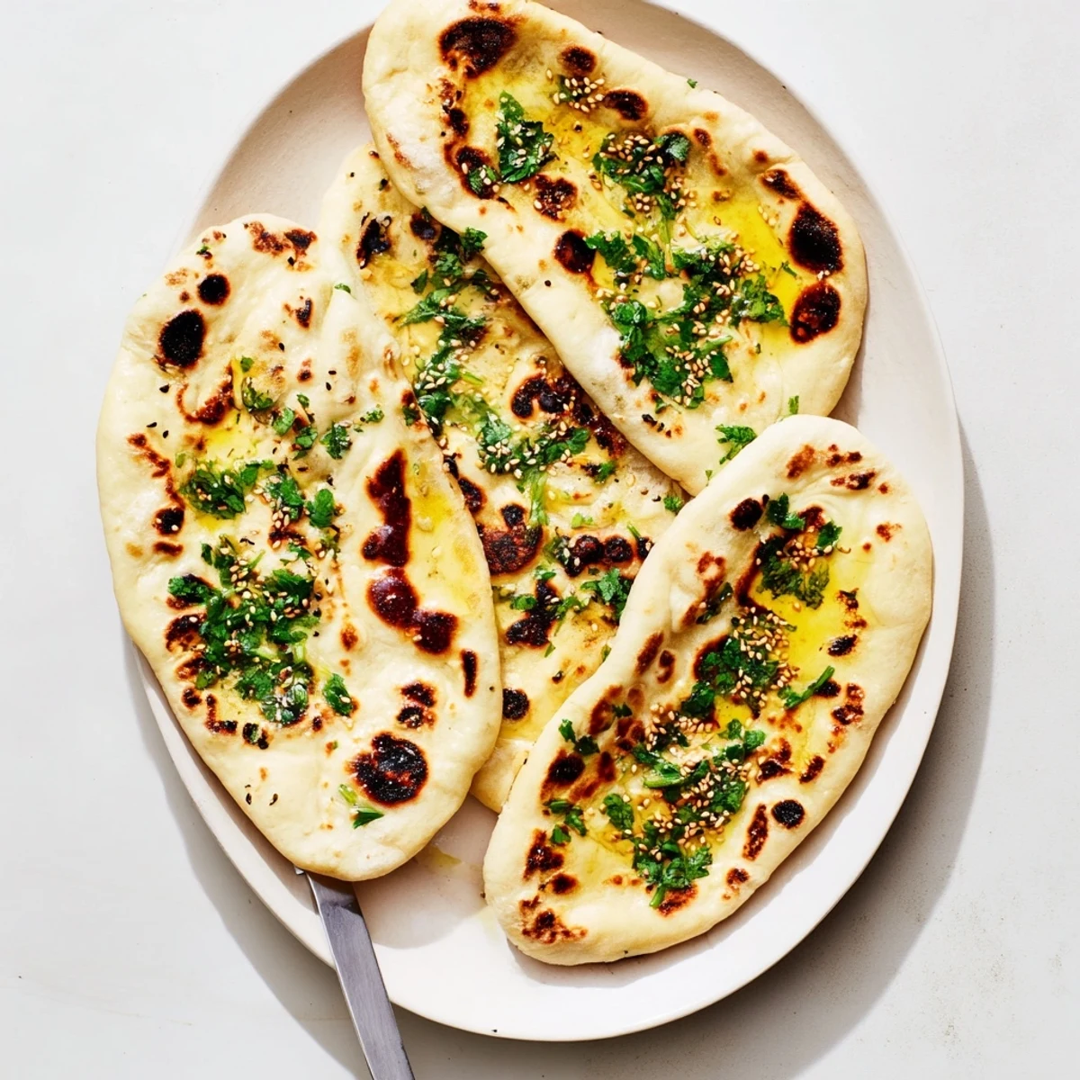 Soft homemade sourdough discard naan cooking in a hot skillet with golden spotted surface