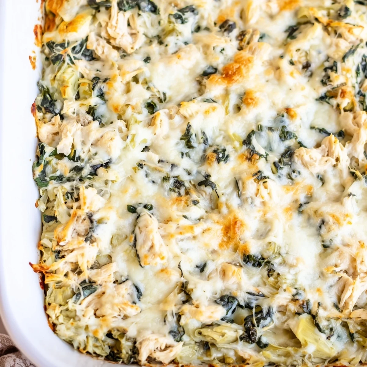 Creamy spinach artichoke chicken casserole fresh from the oven with bubbly cheese topping