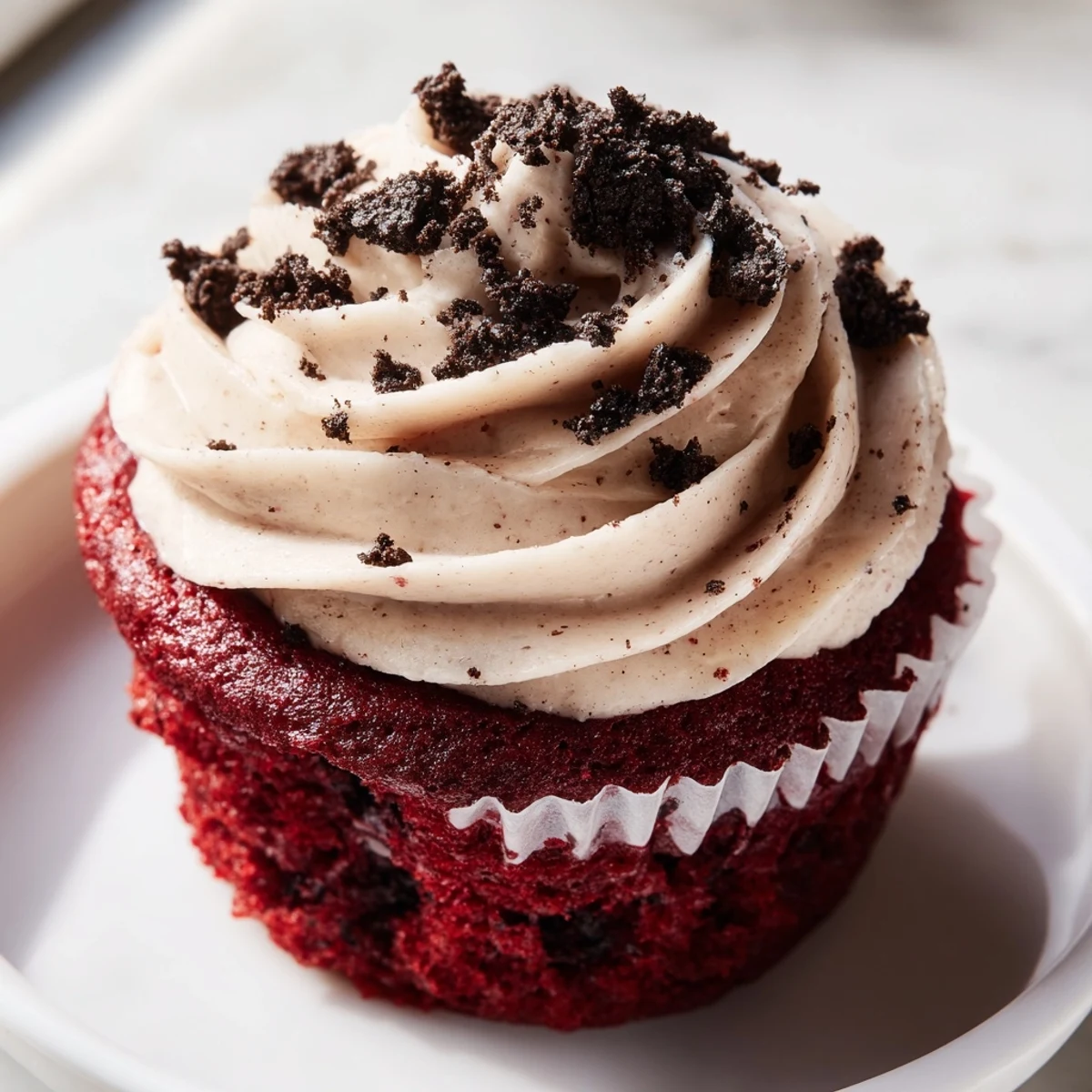 Soft red velvet Oreo cupcakes with tangy cream cheese frosting and chocolate cookie crumbs