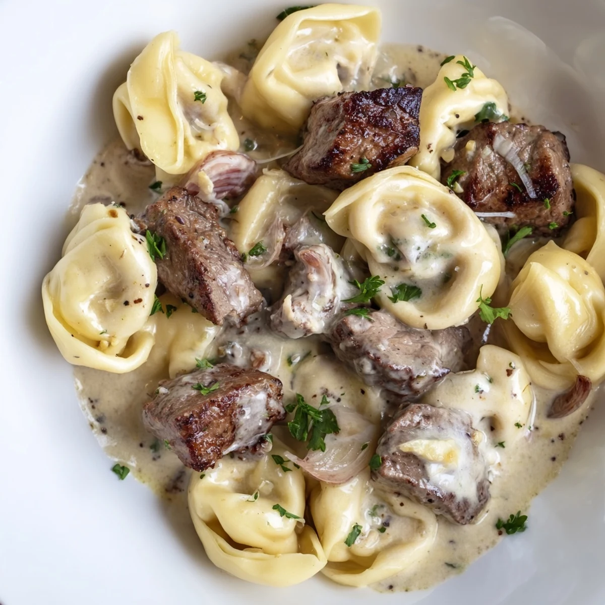 Creamy garlic steak tortellini in a golden parmesan sauce topped with fresh parsley