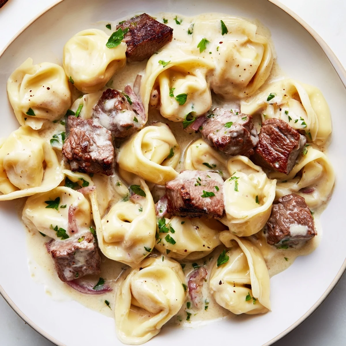 Sizzling steak bites served over cheesy tortellini in a rich garlic cream sauce